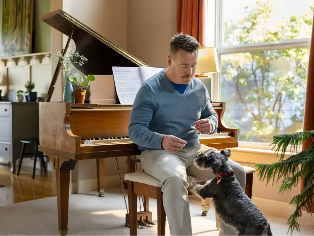 Man sitting at piano, playing with dog